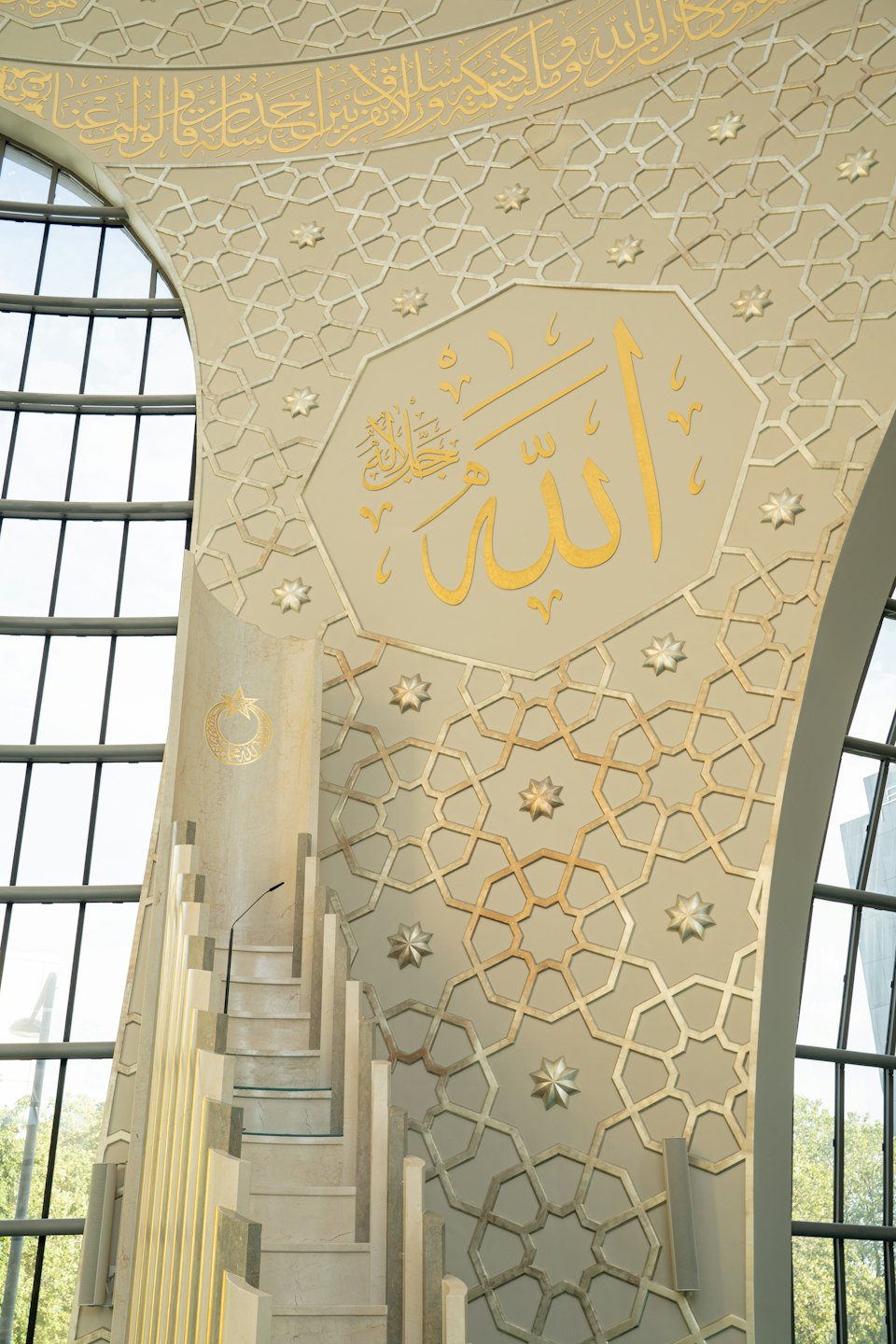 Ornate minbar with golden Arabic calligraphy on a decorated wall.