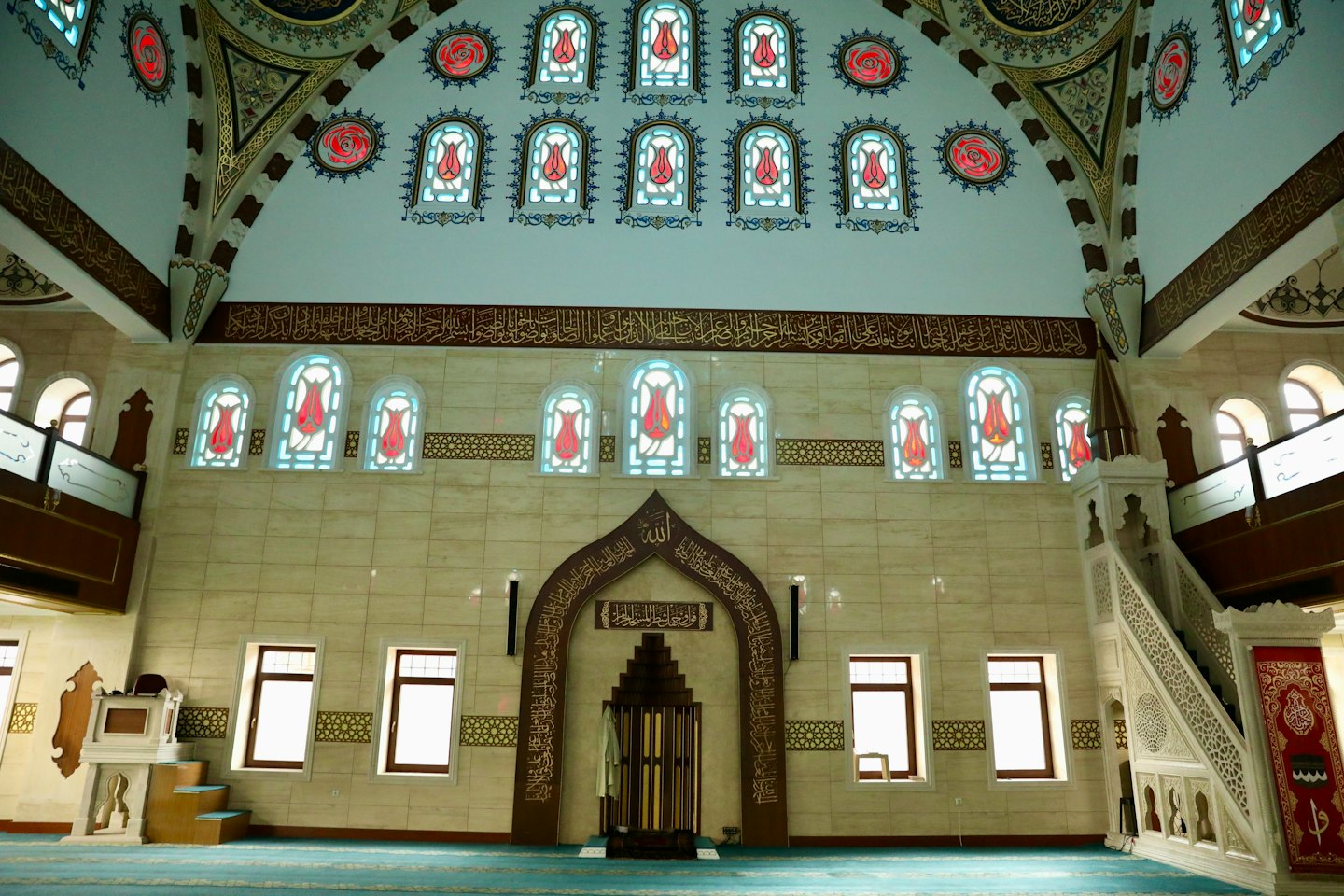Modern mosque prayer hall featuring geometric marble walls and ornate motifs.